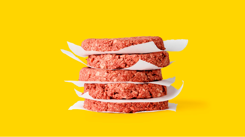 Five vegetarian burger patties are stacked atop each other